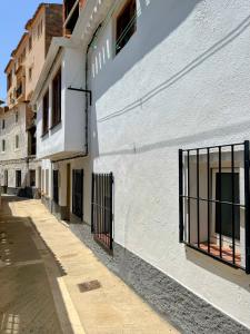 阿尔卡拉德尔胡卡尔Casa cueva del sastre Alcalá del Júcar的白色的建筑,街道上设有黑色的铁窗