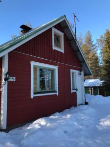 a red house with snow in front of it at Tievaharju Cabin in Kittilä