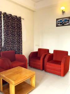 Sala de estar con 2 sillas rojas y mesa de centro en Iris Boutique Hotel, en Jaigaon