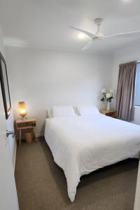 Un dormitorio con una cama blanca grande y una ventana en The Weekend, en Papamoa