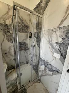een douche in een badkamer met marmeren muren bij Sostal5 in Chiubbica