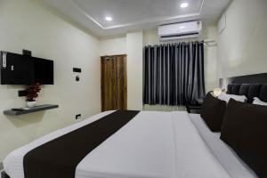ein Schlafzimmer mit einem großen weißen Bett und einem Fernseher in der Unterkunft Super Hotel O EMBASSYINN in Kondapur