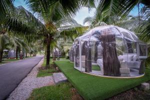 a gazebo with couches and chairs in a yard with palm trees at The Coco Journey - Eco Dome in Malacca