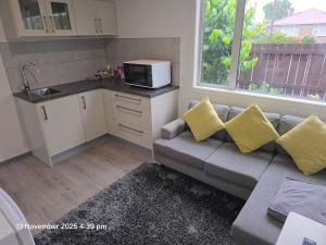 ein Wohnzimmer mit Couch und Mikrowelle in der Unterkunft Manuki Tiny Retreat - Private stay Christchurch in Christchurch
