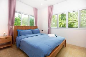Japanese houses in Phuket في Ban Thalat Choeng Thale: غرفة نوم بسرير وملاءات زرقاء ونوافذ