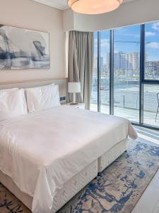 a bedroom with a large white bed with a large window at Marrasi Vista by the address in Muharraq