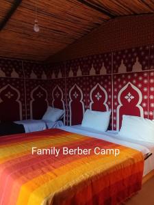 a bedroom with two beds and a red wall at Family Berber Camp in Merzouga