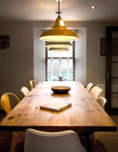 a dining room with a wooden table and a yellow light at Aald Harbour Hoose, Shetland Islands in Lerwick