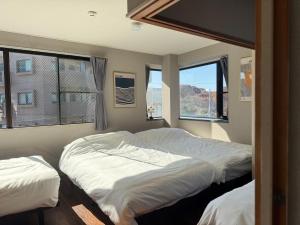 deux lits dans une chambre avec deux fenêtres dans l'établissement UNITED GARDEN hotel 宇都宮駅前3階, à Utsunomiya