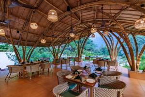 um restaurante com mesas e cadeiras com árvores ao fundo em ONENESS Rishikesh by Ganga Kinare - A Luxury Wilderness Resort em Rishikesh
