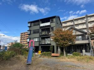 un grand bâtiment avec un panneau rose devant lui dans l'établissement UNITED GARDEN hotel 宇都宮駅前3階, à Utsunomiya