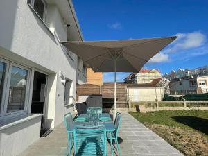a table with chairs and an umbrella on a patio at Ste Cécile Plage in Camiers