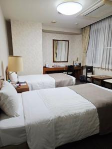 a hotel room with two beds and a desk at UrbanHotelTokyoShinmatsudo in Matsudo