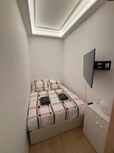 ein weißes Schlafzimmer mit einem Bett und einem Fernseher in der Unterkunft Studio avec chambre inférieure in Cap d'Ail