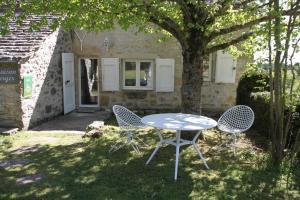Una mesa y dos sillas debajo de un árbol. en La Maison du Berger, en La Cresse