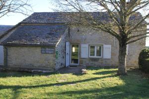 una vieja casa de piedra con un árbol delante en La Maison du Berger, en La Cresse