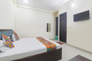 um quarto com uma cama e uma TV de tela plana em FabHotel JP International em Lucknow