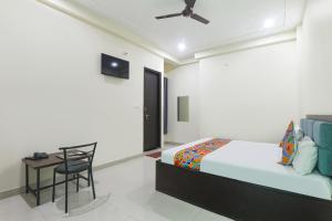 um quarto com uma cama e uma mesa com uma cadeira em FabHotel JP International em Lucknow