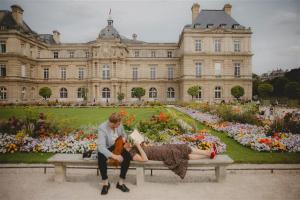 a man and woman sitting on a bench in front of a building at Hotel Le petit Paris in Paris