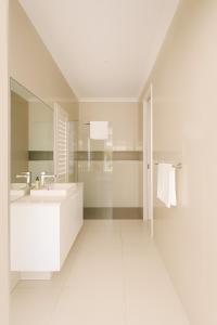 a white bathroom with a sink and a mirror at Creekside Manor - Spacious | Nature & Serenity - Holiday Home in Gold Coast +16 photos