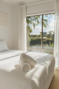 a white bed with towels on it in front of a window at Creekside Manor - Spacious | Nature & Serenity - Holiday Home in Gold Coast