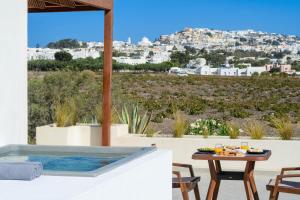 a patio with a table and a hot tub at Safrani Suites in Santorini +82 photos