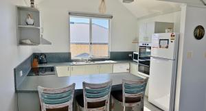 eine Küche mit einem weißen Kühlschrank und Stühlen in der Unterkunft Waterfront Unit 3 - Kalbarri, WA in Kalbarri