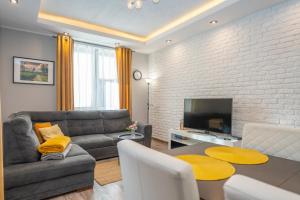 sala de estar con sofá, mesa y TV en Karkonosky Apartamenty- Salamandra, en Szklarska Poręba