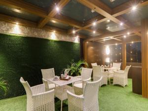 a restaurant with white chairs and a green wall at Super Hotel O Centrum in Gorakhpur