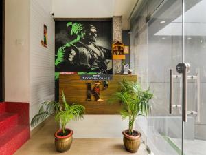 two potted plants in front of a wall with a poster at Super Hotel O Centrum in Gorakhpur