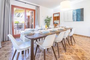 a dining room with a long table and white chairs at Villa Ribera de Son Veri in El Arenal