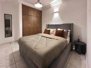 1 dormitorio con 1 cama grande con almohadas marrones en Aiah Cocoon, en Abiyán