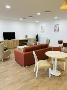 a living room with a couch and tables and a tv at Nouvelles Sylphides in Carrières-sous-Poissy