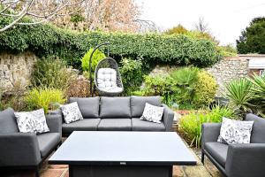 a patio with couches and a table in a garden at Gate Cottage, Saltwood Village in Hythe