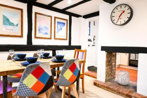 a dining room with a table and a clock on the wall at Gate Cottage, Saltwood Village in Hythe