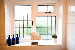 ein Fenster mit Flaschen und ein Huhn auf einem Regal in der Unterkunft Gate Cottage, Saltwood Village in Sandling Junction + 57 Fotos