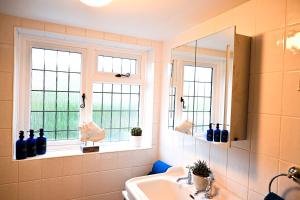 a bathroom with a sink and two windows at Gate Cottage, Saltwood Village in Hythe +29 photos