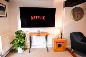 a living room with a netflix sign on the wall at Gate Cottage, Saltwood Village in Hythe