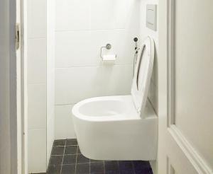 a white toilet with the seat up in a bathroom at Harjutori Studio Flat, A quiet park close to the city centre and the airport in Helsinki