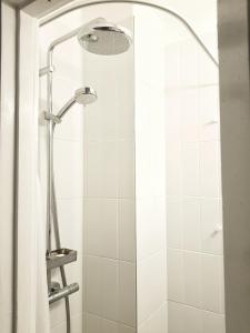 a shower with a shower curtain and a shower head at Harjutori Studio Flat, A quiet park close to the city centre and the airport in Helsinki