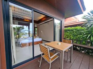 einen Holztisch und Stühle auf einem Balkon mit einem Schlafzimmer in der Unterkunft Kaya Mani Thai Villa resort in Strand Choeng Mon