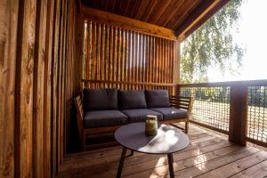 a porch with a couch and a table on a deck at Chalet confort, Proche Puy duFou, plan d'eau privé in Menomblet