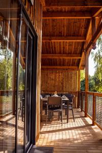 a wooden deck with a table and chairs on it at Chalet confort, Proche Puy duFou, plan d'eau privé in Menomblet
