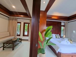 ein Schlafzimmer mit einem Bett, einer Couch und einem Tisch in der Unterkunft Kaya Mani Thai Villa resort in Strand Choeng Mon