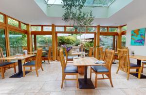 a restaurant with wooden tables and chairs and windows at Dorian House Boutique B&B - Free Parking! in Bath +24 photos