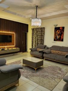 Una sala de estar con sofás y una lámpara de araña. en AIN LUXE Stay, en Idogwari