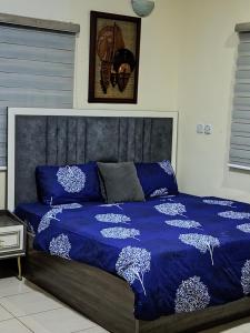 1 cama con edredón azul y almohadas en AIN LUXE Stay, en Idogwari
