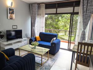 a living room with a blue couch and a tv at Kampala suites Kisementi in Kampala