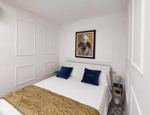 a white bedroom with a bed with blue pillows at Casa Del Duca in Salerno