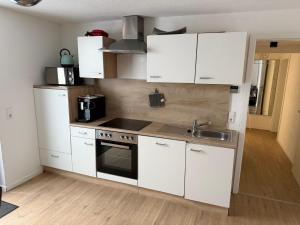 Una cocina con gabinetes blancos y un fregadero. en Moderne gemütliche Ferienwohnung in Friedrichshafen, en Friedrichshafen